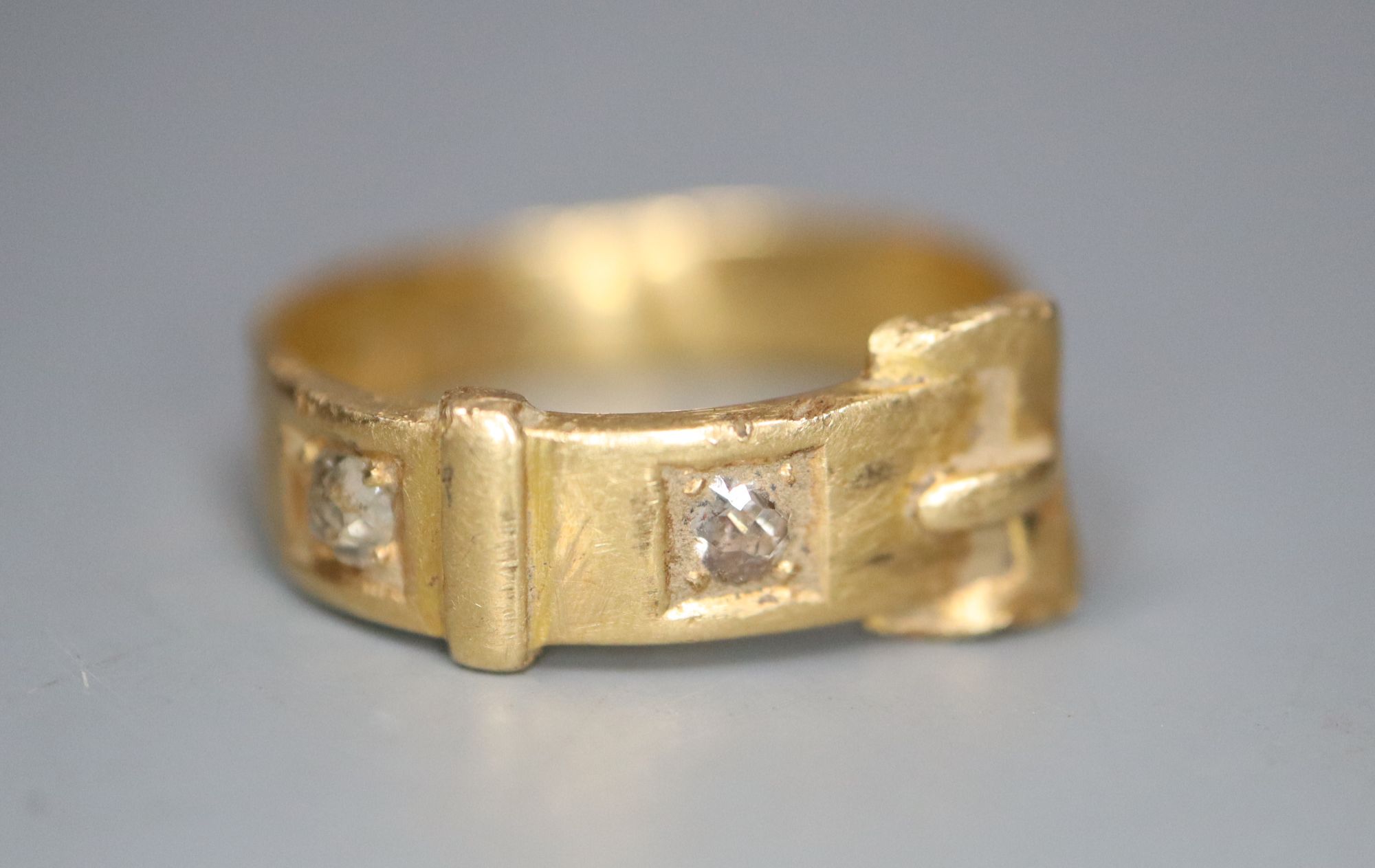 An early 20th century 18ct? gold and two stone diamond set buckle ring, size I, gross 4.1 grams.